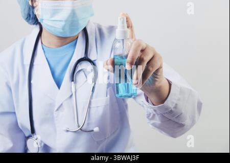 Le médecin vaporise du désinfectant pour les mains ou un distributeur de gel pour nettoyer les mains et tuer les virus et les bactéries dans l'air après la visite des patients. Les personnes de santé médicale Banque D'Images