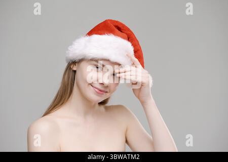 Femme de Noël. Modèle de beauté dans Santa Hat isolé sur fond gris. Drôle de rire surpris femme portrait longueur épaule. Sourit avec des dents. Re Banque D'Images