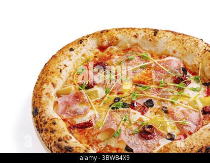 La pizza gastronomique fraîchement cuite présente un bord croustillant garni de jambon, de tomates séchées et d'herbes délicates, prêtes à être dégustées. Parfait pour un décontracté Banque D'Images