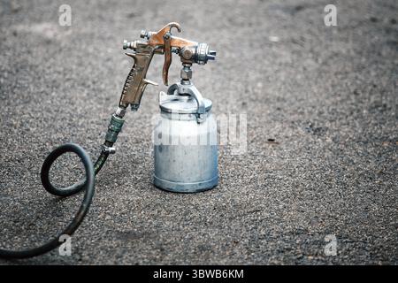 Un vieux pistolet se tient sur l'asphalte. Thème de la peinture industrielle. Gros plan Banque D'Images