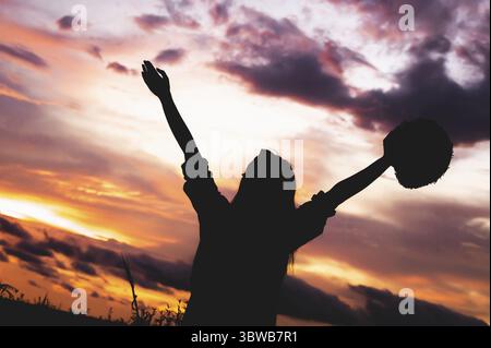 Silhouette de femme heureuse bras ouverts sous le lever du soleil au bord de la mer avec fond de coucher de soleil pendant le voyage en vacances. Forte confiance joyeuse fille avec daw Banque D'Images