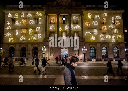 15 décembre 2020, Barcelone, Catalogne, Espagne : à Barcelone, des personnes portant des masques passent devant la façade de l'hôtel de ville décorée de figures lumineuses de Noël. (Crédit image : © Jordi Boixareu/ZUMA Wire) Banque D'Images