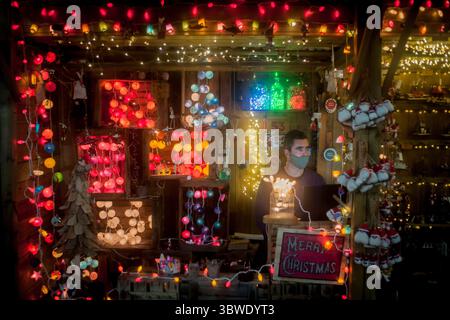 15 décembre 2020, Barcelone, Catalogne, Espagne : à un stand de lumières décoratives dans le marché de Noël Santa Llucia de Barcelone, un vendeur portant un masque facial attend les clients. (Crédit image : © Jordi Boixareu/ZUMA Wire) Banque D'Images