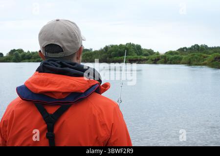 Retour de mature Man pêchant du bateau sur la rivière. Banque D'Images