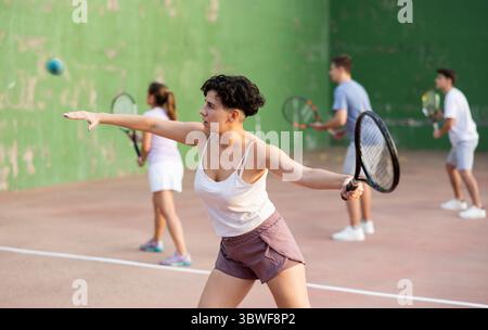 Femme servant le ballon pendant le jeu frontenis à l'extérieur Banque D'Images