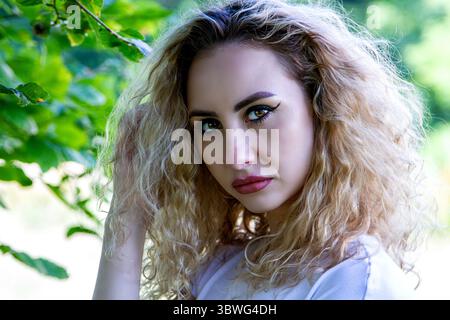 Un beau modèle moldave blonde pose sur une journée ensoleillée de juillet sous la canopée d'arbres au Dundee Camperdown Country Park en Écosse, au Royaume-Uni Banque D'Images