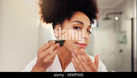 Femme, portrait et gua Sha pour le massage facial dans la salle de bain pour la routine du matin, les soins de la peau et l'antivieillissement. Visage, pov et personne africaine pour naturel Banque D'Images