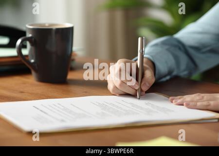 Gros plan portrait d'un employé de bureau des mains signant contrat sur la table en bois Banque D'Images