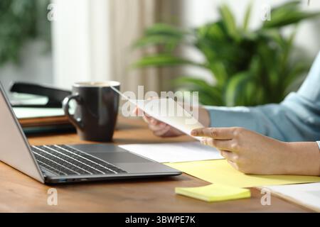 Gros plan d'une femme mains tenant un document en papier sur une table en bois au bureau Banque D'Images