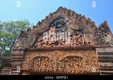 Gros plan d'une scène mythologique sculptée dans du grès rose sur un pignon de temple à Banteay Srei, Cambodge. Banque D'Images