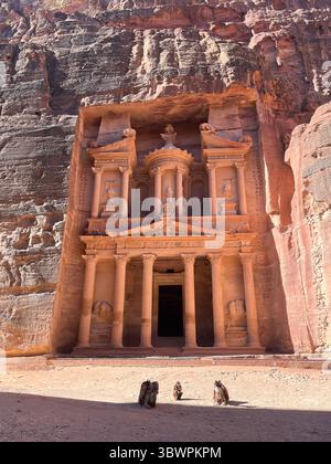 Le Trésor (Al-Khazneh) à Pétra, Jordanie – majestueux temple nabatéen creusé dans des falaises de grès rouge avec des chameaux reposant devant. Banque D'Images