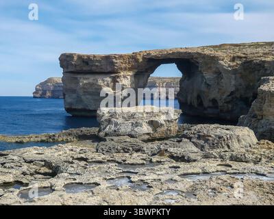 Azure Window, une arche calcaire naturelle sur l'île de Gozo à Malte, avec une mer bleue et une côte rocheuse sous un ciel partiellement nuageux. Banque D'Images
