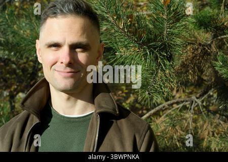 L'homme rayonne de joie sur fond de feuilles luxuriantes et d'arbres dans la nature. Banque D'Images
