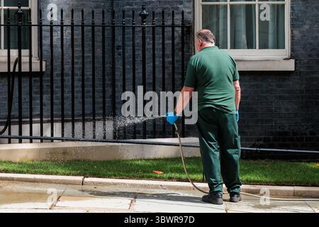 Londres, Royaume-Uni. 15 juillet 2025. Un homme utilise un tuyau d'arrosage pour arroser l'herbe dans Downing Street. Il n'y a actuellement pas d'interdiction de canalisations à Londres, mais Thames Water Banque D'Images