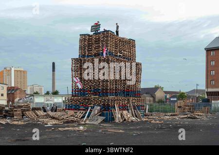 10 juillet 2021, Belfast, Ulster, Royaume-Uni : un bûcher construit de palettes en bois est érigé dans une cour de la rue Wellwood en préparation des célébrations de feu de joie de la onzième nuit qui ont lieu chaque année dans toute l'Irlande du Nord pour célébrer la victoire du roi protestant Guillaume d'Orange sur le roi catholique Jacques II à la bataille de la Boyne (1690), qui a commencé l'ascension protestante en Irlande. préparatifs en lieu de la nuit de feu de feu de juillet 11 à Belfast avant les marches annuelles de l'ordre orange du 12 juillet. Cette année marque le centenaire de la formation de l'Irlande du Nord et moi-même Banque D'Images