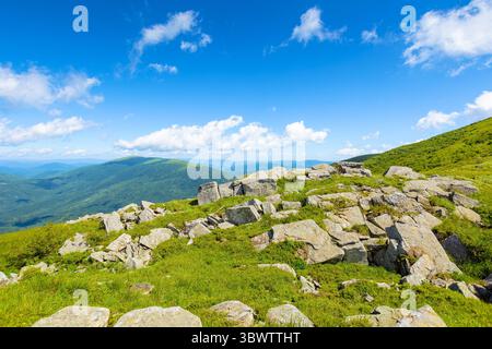 magnifique paysage de montagne en été. paysage large avec de la roche parmi l'herbe sur les collines et les pentes sous le ciel bleu avec des nuages moelleux à midi élevé. sce Banque D'Images