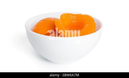 Pêches en conserve dans un bol blanc. Pêches douces au sirop isolé sur fond blanc. Photo de haute qualité Banque D'Images