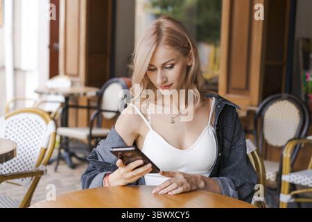 Blonde belle femme caucasienne élégante dans une tenue décontractée marchant le long du centre-ville Banque D'Images
