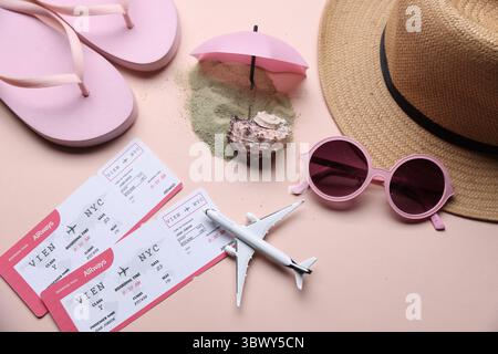 Billets d'avion, modèle d'avion, sable et accessoires de plage sur fond beige, pose plate Banque D'Images