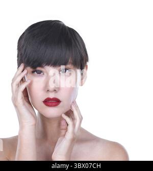 Un superbe portrait de beauté en studio d'une femme asiatique de race mixte avec un contact visuel intense et un rouge à lèvres rouge profond, ses mains encadrant doucement son visage. Thi Banque D'Images