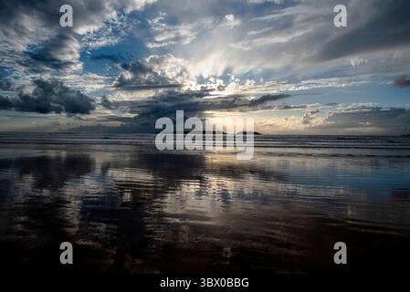 Coucher de soleil sur les vastes plages d’Essaouira avec un ciel bleu, des nuages blancs et des vagues s’écrasant sur le rivage au Maroc Banque D'Images
