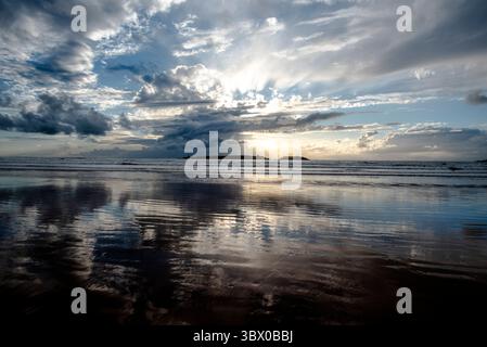 Coucher de soleil sur les vastes plages d’Essaouira avec un ciel bleu, des nuages blancs et des vagues s’écrasant sur le rivage au Maroc Banque D'Images