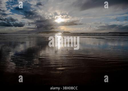 Coucher de soleil sur les vastes plages d’Essaouira avec un ciel bleu, des nuages blancs et des vagues s’écrasant sur le rivage au Maroc Banque D'Images