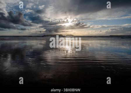 Coucher de soleil sur les vastes plages d’Essaouira avec un ciel bleu, des nuages blancs et des vagues s’écrasant sur le rivage au Maroc Banque D'Images