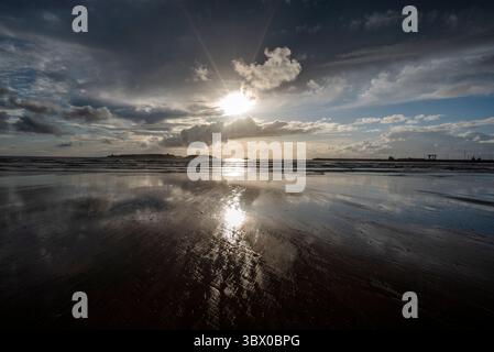 Coucher de soleil sur les vastes plages d’Essaouira avec un ciel bleu, des nuages blancs et des vagues s’écrasant sur le rivage au Maroc Banque D'Images