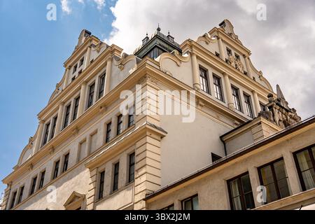 Architecture bavaroise historique à Munich : bâtiment d'angle jaune avec Tour du dôme vert, fenêtres ornées, boîtes à fleurs et toit escarpé sous Cl Banque D'Images