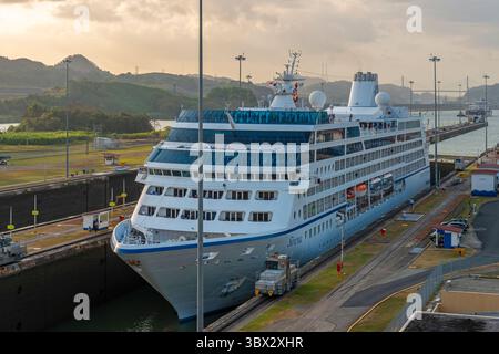 Bateau de croisière passant les écluses de Miraflores du canal de Panama au coucher du soleil dans la ville de Panama, Panama. Banque D'Images