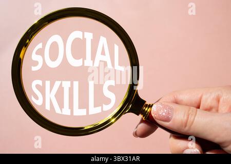 Symbole de compétences sociales. Mots conceptuels compétences sociales sur la loupe. Beau fond rose. Main d'homme d'affaires. Business and social Skills concept Banque D'Images