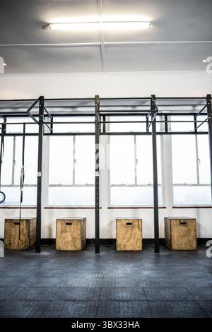 Anneaux de gymnastique par des boîtes dans la salle de gym éclairée Banque D'Images