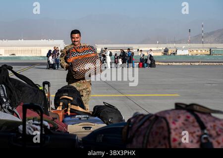 STYLELOCATIONA un aviateur de l'armée de l'air américaine déplace les bagages alors que des réfugiés afghans montent à bord d'un avion C-17 Globemaster III de l'armée de l'air lors de l'évacuation de l'aéroport international Hamid Karzai pendant l'opération refuge Allies le 24 août 2021 à Kaboul, en Afghanistan. (Crédit image : © Sra Taylor Crul/U.S. Air/Planet Pix via ZUMA Press Wire) Banque D'Images