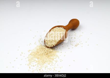 Graines de sésame dans une cuillère en bois, isolées sur fond blanc. Graines de sésame sèches organiques. Banque D'Images
