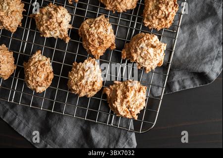 Macarons cuits au four sur une grille de refroidissement en treillis métallique gros plan : des biscuits fraîchement cuits à la noix de coco et à la meringue laissent refroidir sur une grille métallique Banque D'Images