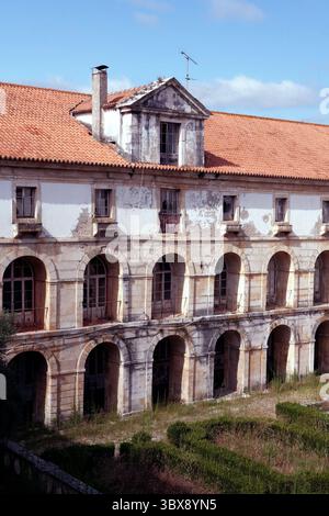 Façade altérée de l'aile du cloître du monastère d'Alcobaça, avec peinture écaillée et galeries en pierre voûtée Banque D'Images