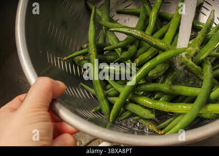 Gros plan de haricots verts frais rincés dans une passoire dans la cuisine Banque D'Images