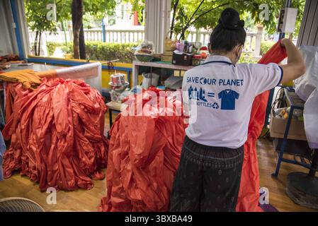6 octobre 2021, Samut Prakarn, Thaïlande : une femme est vue avec un costume d'équipement de protection individuelle (EPI) pour les moines bouddhistes qui travaillent comme bénévoles à Wat Chak Daeng à Samut Prakarn..L'administration et les temples de la ville de Bangkok mènent des efforts pour encourager le public à donner des bouteilles en plastique, qui sont ensuite collectées et recyclées en équipement de protection individuelle réutilisable (EPI) et robes jaunes pour les moines bouddhistes pour réduire les déchets plastiques alors que la Thaïlande continue de lutte contre la pandémie de coronavirus-19) à Bangkok. (Crédit image : © Peerapon Boonyakiat/SOPA images via ZUMA Press Wire) Banque D'Images