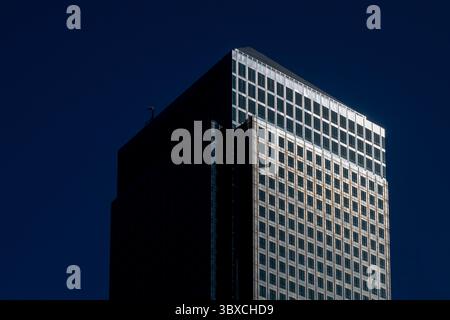 Gratte-ciel moderne à Canary Wharf, Londres, fortement éclairé par la lumière du soleil contre un ciel bleu profond - symbole de la finance mondiale et du pouvoir des entreprises. Banque D'Images