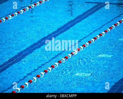 Piscine avec séparateurs de voie et eau bleue claire. Le sol carrelé bleu est visible sous la surface, créant une scène de sport rafraîchissante, leis Banque D'Images