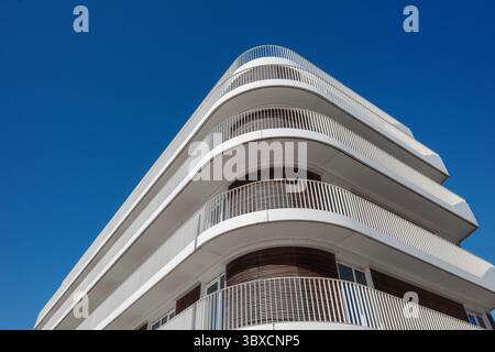 Une vue panoramique de l'extérieur d'un immeuble moderne blanc. La conception architecturale comporte des balcons courbes proéminents. Banque D'Images