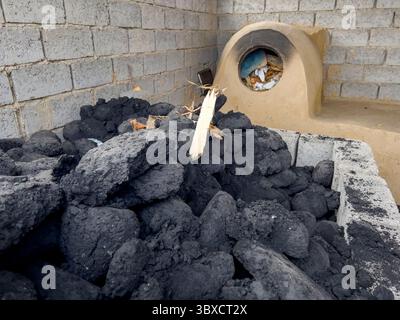 Cuisson traditionnelle du pain au four à argile avec briques de charbon en Ouzbékistan rural Banque D'Images