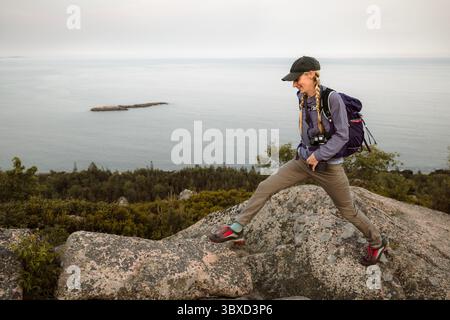 Femme saute de roche en roche en randonnée dans le parc national Acadia Banque D'Images