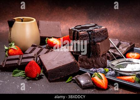 Brownies au chocolat noir et baies. Pile de biscuits maison au brownie avec sauce au chocolat et fraise fraîche, myrtille, sur d Banque D'Images