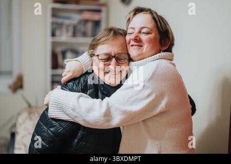 Femme senior et jeune adulte partageant une étreinte chaleureuse dans une chambre confortable Banque D'Images