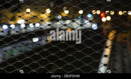 L'éclairage de la ville floues dans la nuit par le biais de barrières - Résumé Banque D'Images