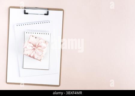 Nourriture, composition festive : une boîte cadeau attachée avec un ruban, un carnet sur une table rose Banque D'Images