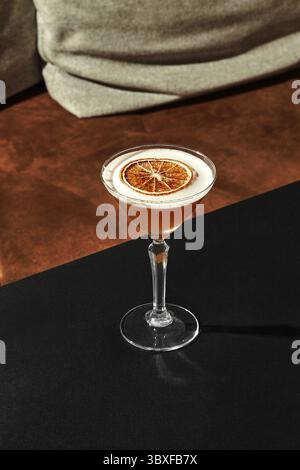 Élégant verre de cocktail aigre d'amande avec saveur rafraîchissante légèrement sucrée et acidulée et dessus mousseux décoré avec une tranche de pamplemousse séchée, présenté o Banque D'Images