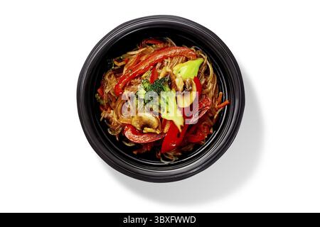 Bol de délicieux nouilles de riz sautées au brocoli, poivrons et champignons, vue de dessus isolée sur fond blanc. Végétari asiatique traditionnel Banque D'Images